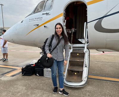 Woman stands outside by the stairs of a small plane