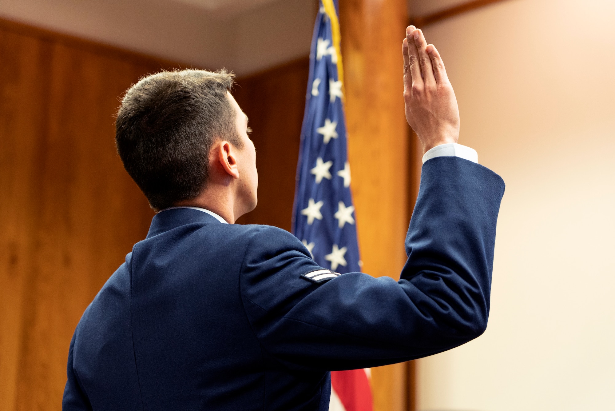 Airman 1st Class Minick stands with his right hand raised during the Oath of Allegiance.