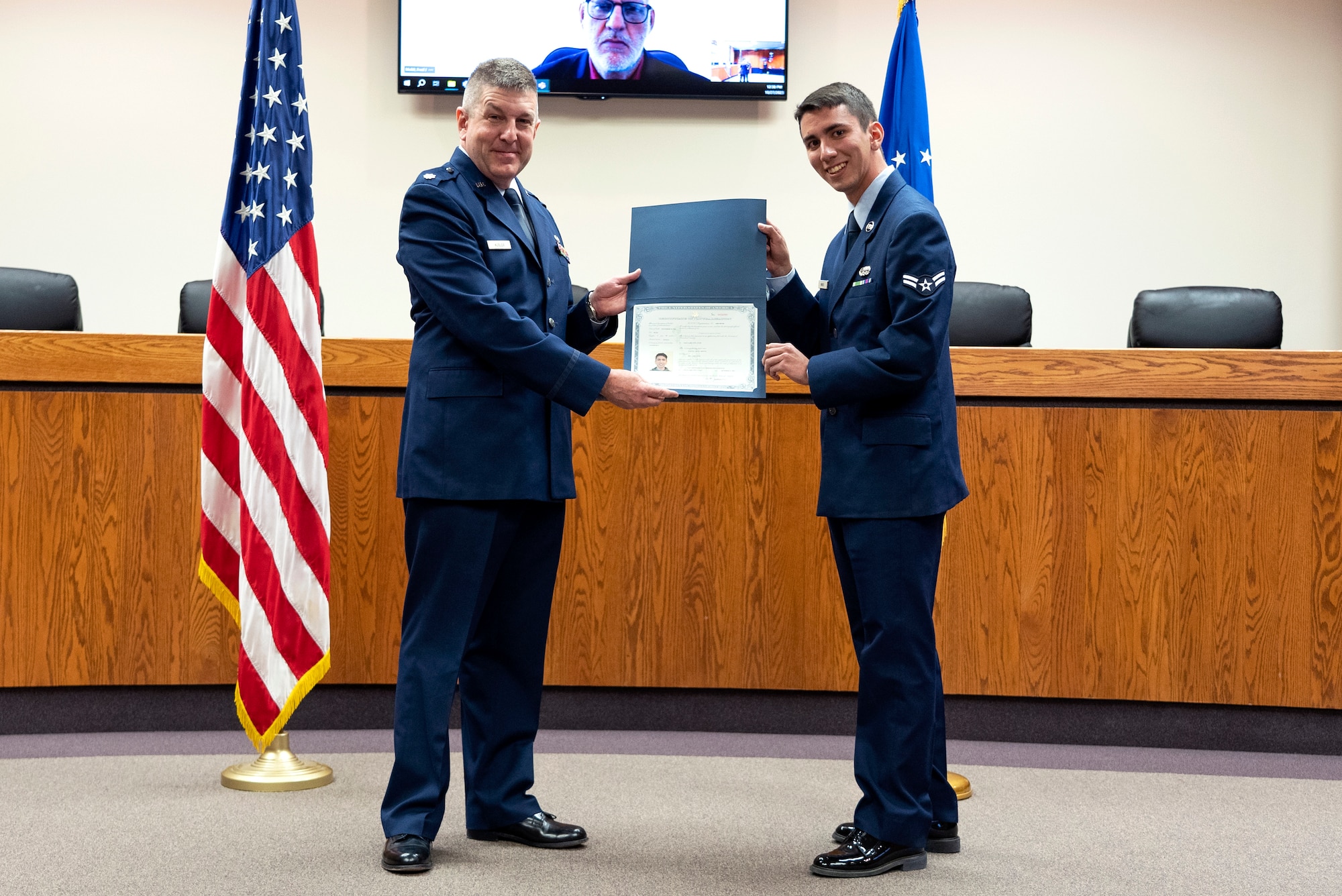Lt. Col. Joseph J. Kubler at left, holding a citizenship certificate with Airman 1st Class Lowell Minick at right.