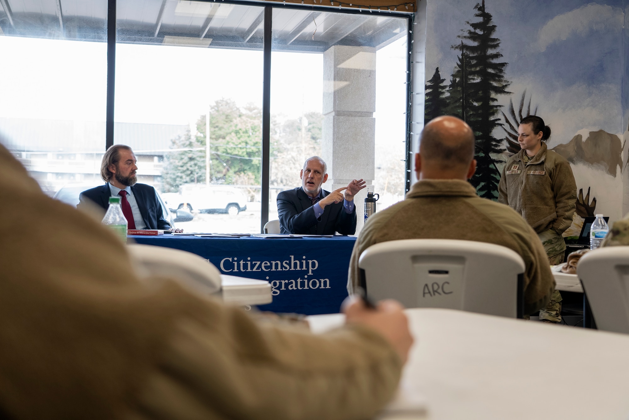 Representatives from the United States Citizenship and Immigration Services sit at a table briefing service members and families.