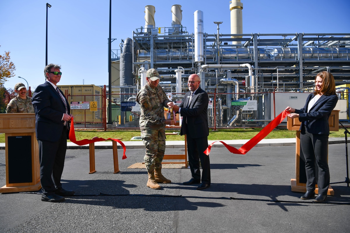 Two people cut a ribbon to unveil the new power plant.