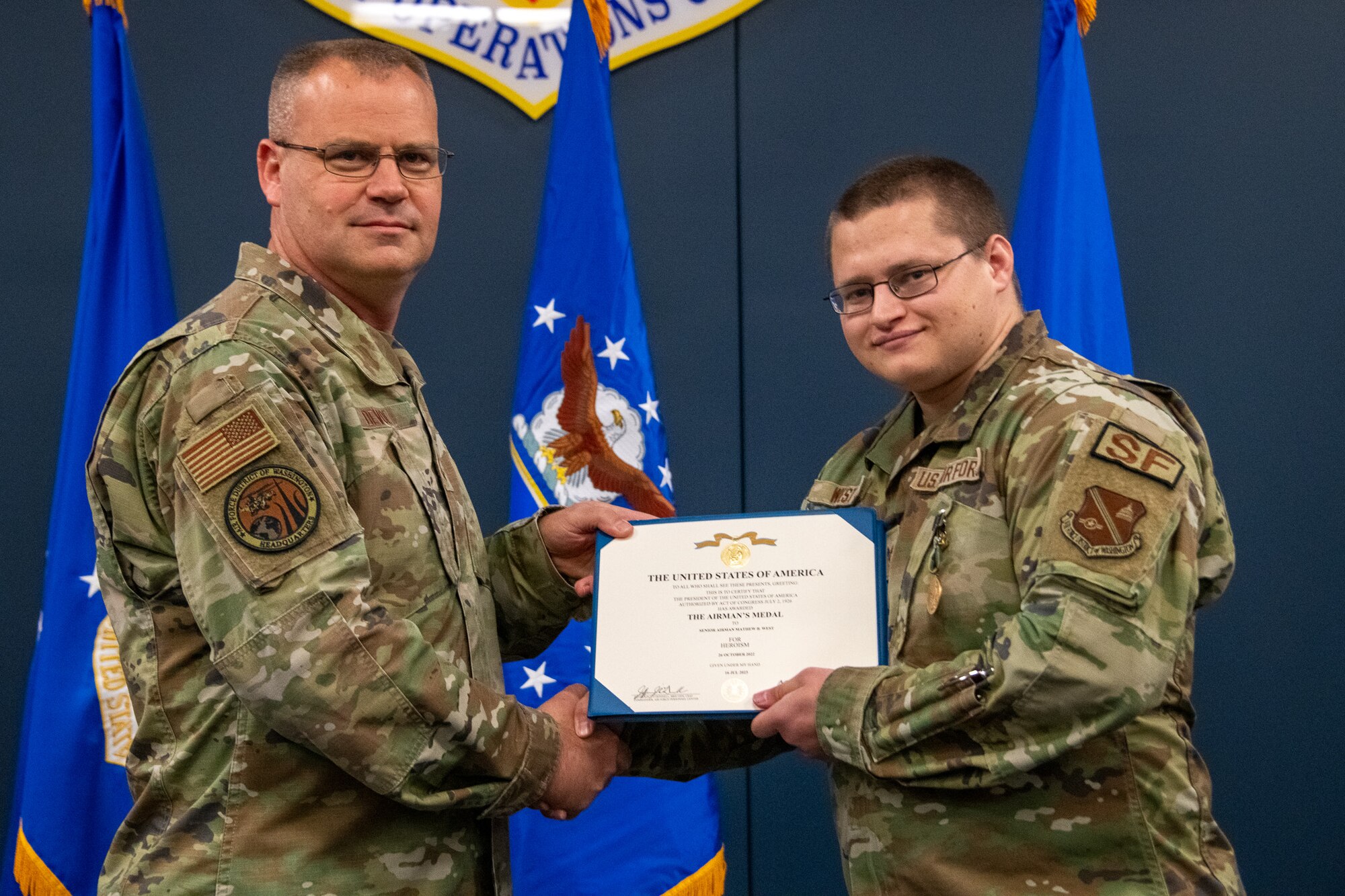 Maj. Gen. Daniel A. DeVoe presents a certificate to Senior Airman Matthew B. West.