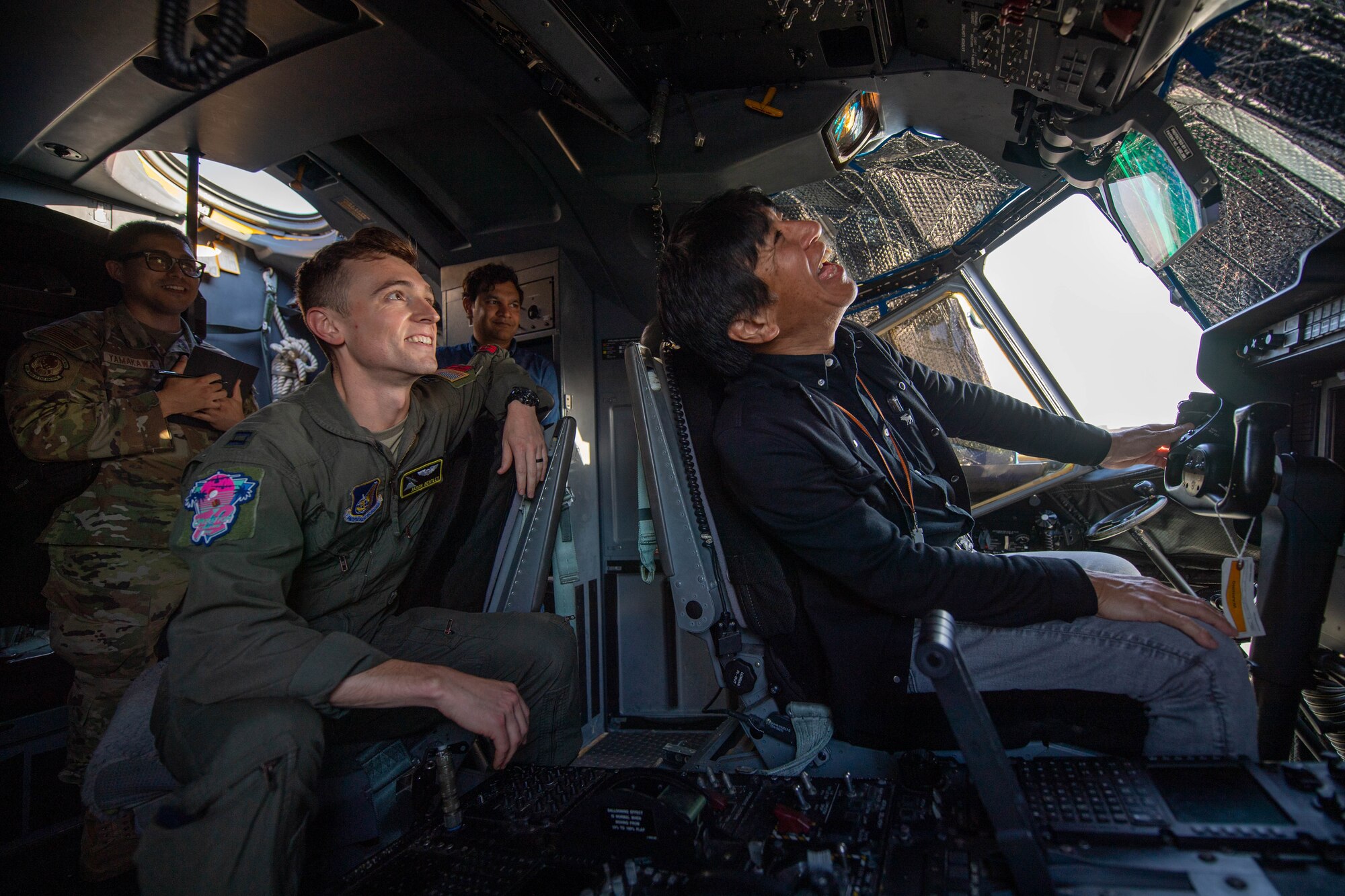 A U.S. Air Force pilot sits in the cockpit of a military aircraft with a Japanese civilian.