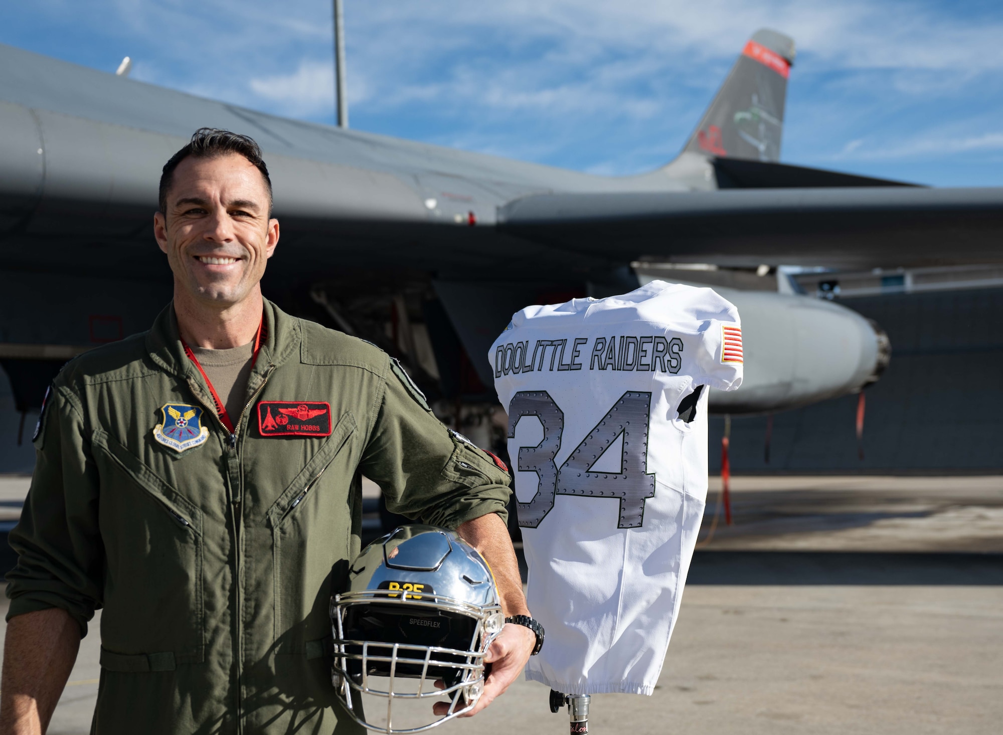 Lt. Col. Hobbs, 37th Bomb Squadron commander poses for a photo with the Air Force Academy’s 2023 Air Power Legacy Series Heritage jersey and helmet on Ellsworth Air Force Base Nov. 2, 2023. Hobbs is slated to lead a training exercise that includes a flyover of two B-1B Lancers for the game in which these heritage uniforms will be worn. (U.S. Air Force photo by Spc3 Adam Olson)