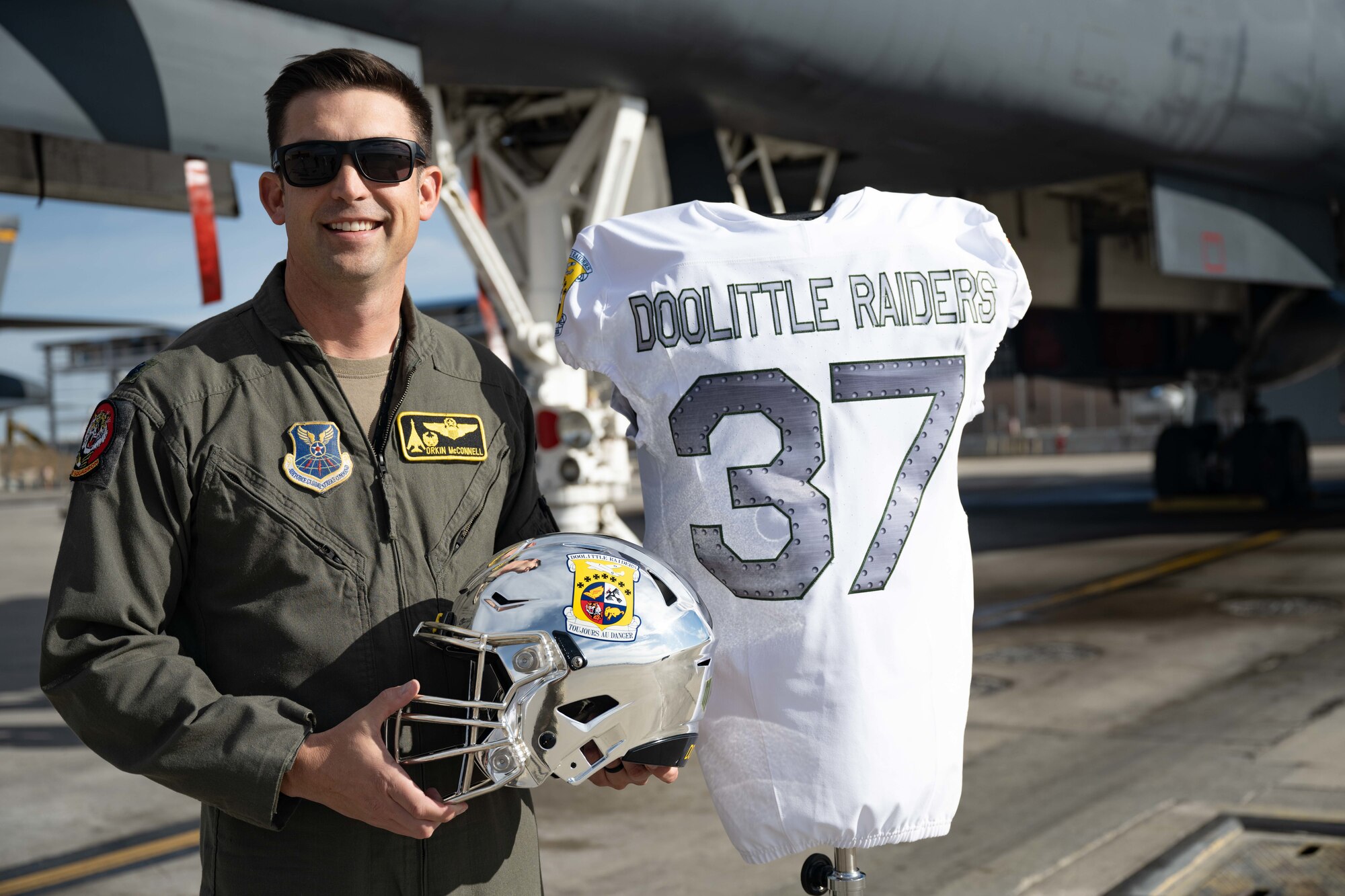 Lt. Col. Christopher McConnell, 37th Bomb Squadron commander, poses for a photo with the Air Force Academy’s 2023 Air Power Legacy Series Heritage jersey and helmet on Ellsworth Air Force Base Nov. 2, 2023. These jerseys are set to be worn during the United States Air Force Academy Falcons versus University of Las Vegas Rebels game on Nov. 18, 2023. (U.S. Air Force photo by Spc3 Adam Olson)