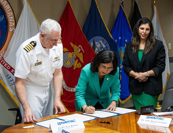 University of Guam President Anita Borja Enriquez, center, signs the Memorandum of Understanding to formalize an internship pathway for UOG’s engineering students on Nov. 1, 2023. Capt. Troy Brown, Commanding Officer of Naval Facilities Engineering Systems Command Marianas, left, signs for NAVFAC as Bharti Hemlani, Lead Human Resources Specialist and acting HR Director at NAVFAC Marianas, facilitates.
