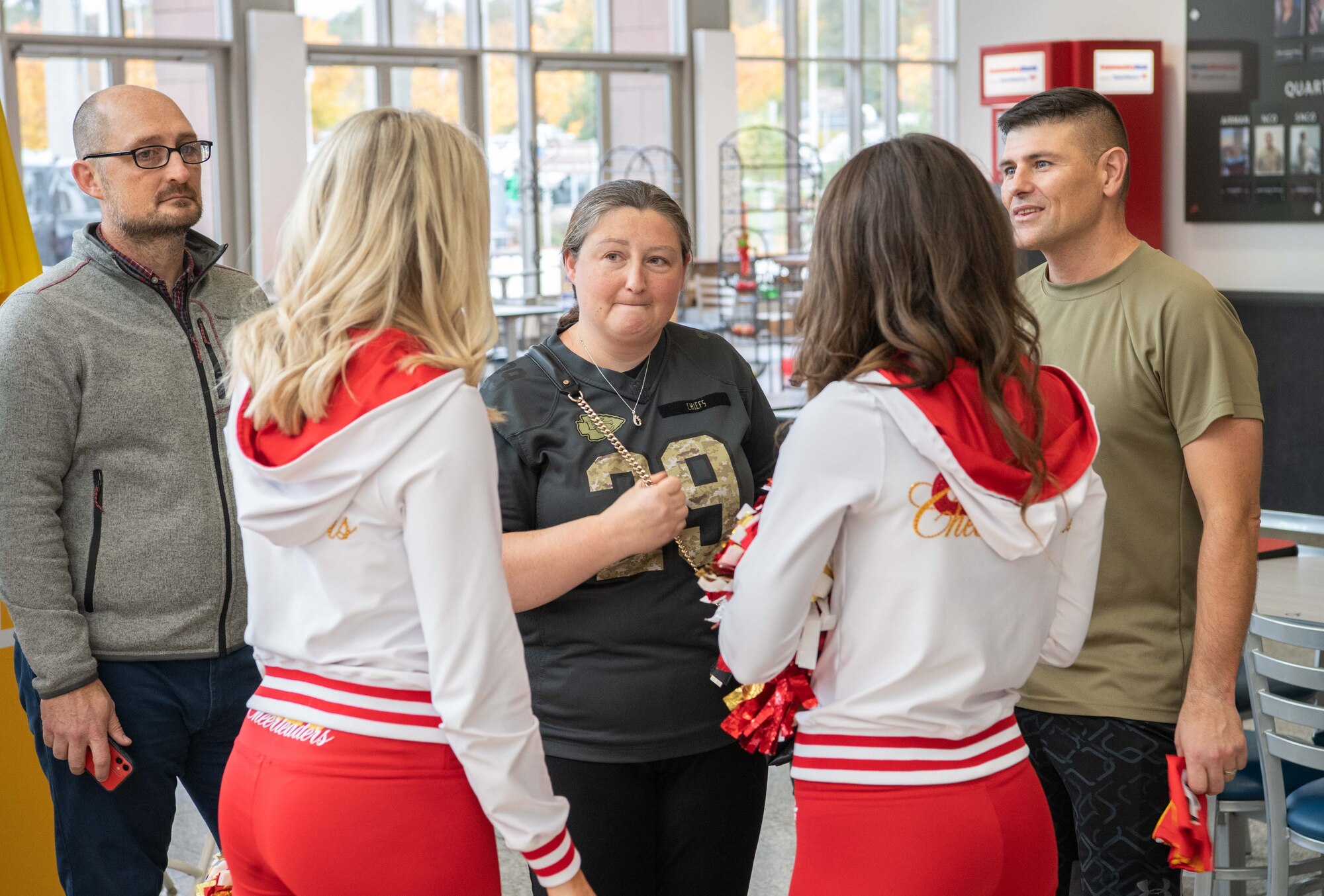 Two cheerleaders talk to three people
