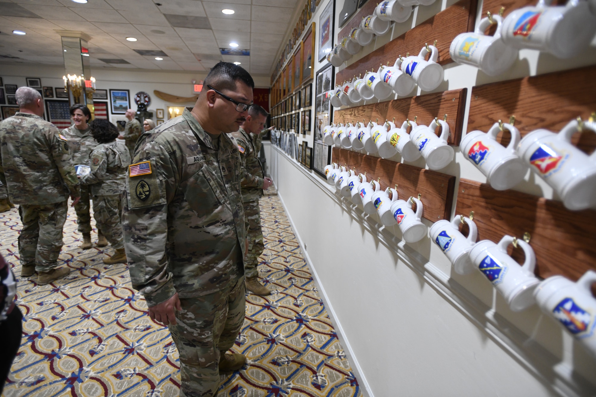 Guam Army National Guard Staff Sgt. Joseph B. Aquino looks at rows of beer steins with emblems from 90 Air National Guard wings during the opening ceremony at The 1636 Room at Joint Base Myer-Henderson Hall’s Patton Hall in Arlington, Virginia, Nov. 1, 2023. Army Gen. Daniel Hokanson, chief of the National Guard Bureau, said the intent of The 1636 Room is to offer a heritage exhibit where Guard members can gather for events and social occasions and for others to learn more about the force.