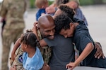 Airman hugging kids.