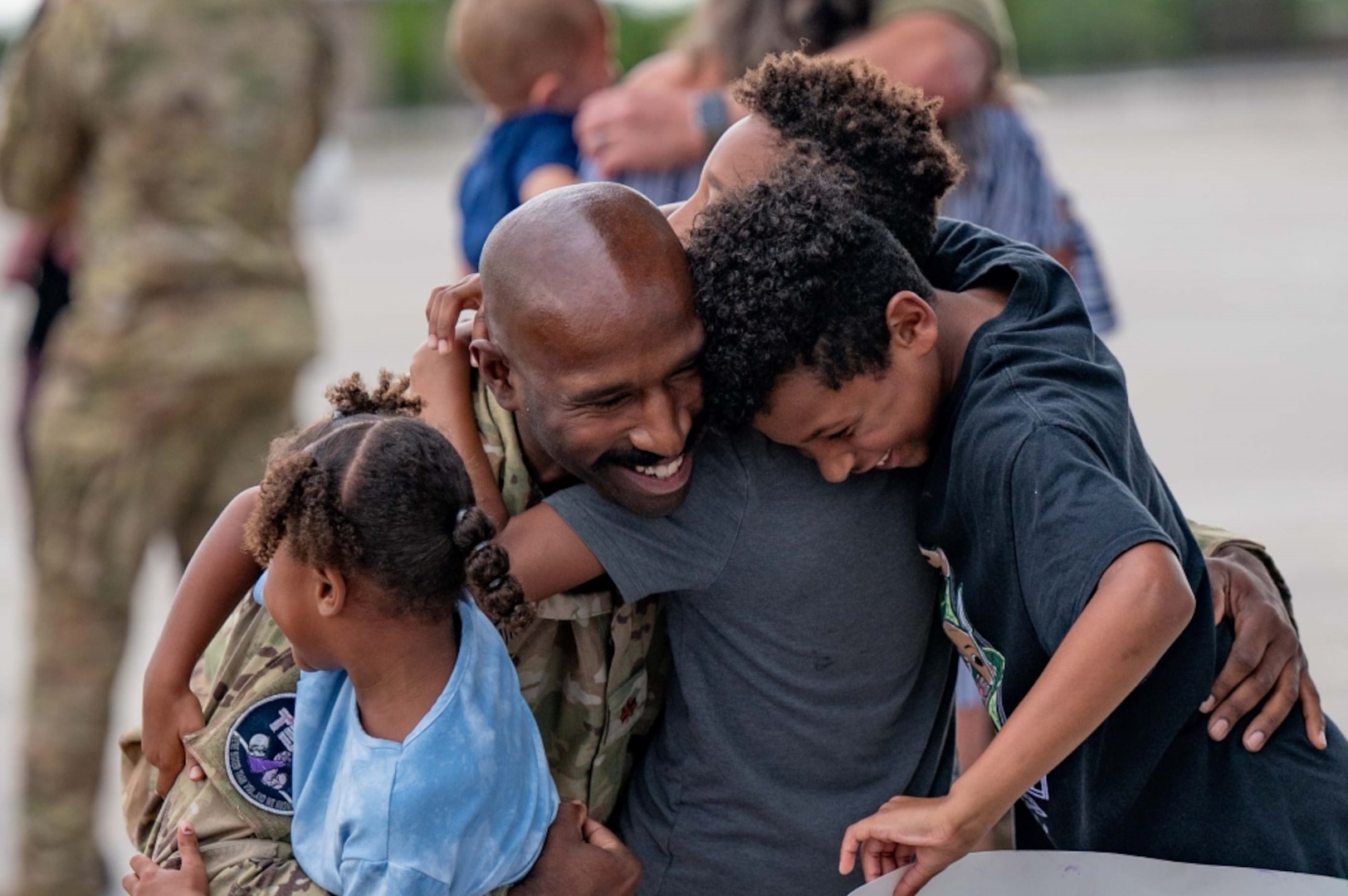 Airman hugging kids.