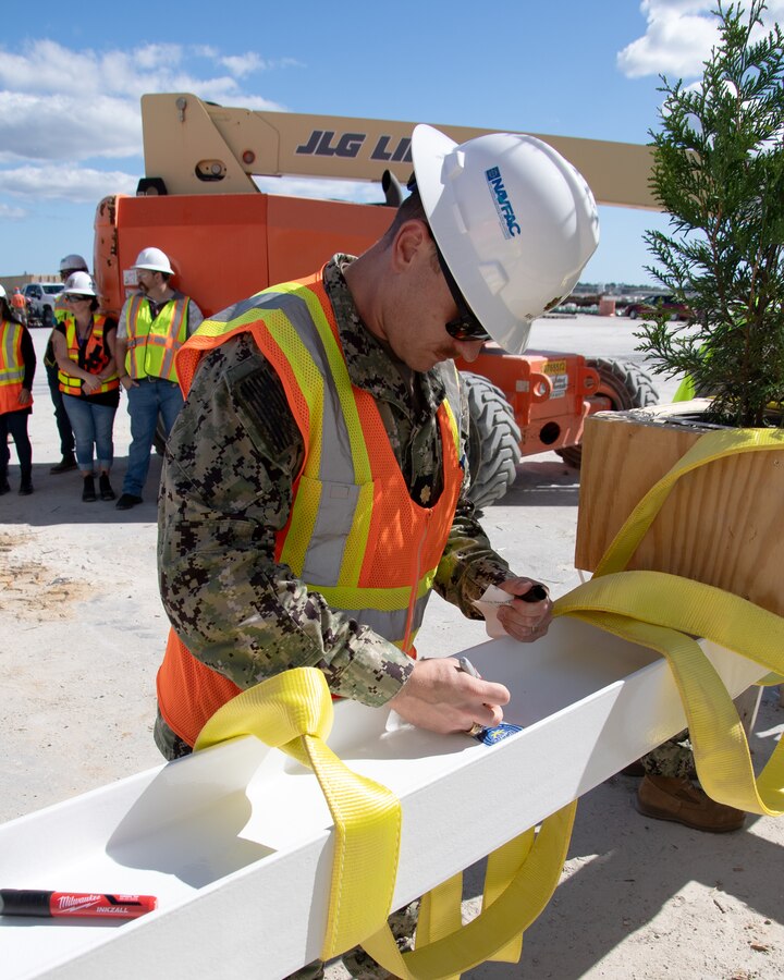 U.S. Navy LCDR Brian Mack, operations officer, Officer in Charge of Construction Florence signs a ceremonial beam on October 25, 2023 aboard Marine Corps Air Station New River. 

Contractor of record, Archer Western of The Walsh Group, hosted a Topping Out ceremony for OICC Florence and Marine Corps representatives to gather and sign the final roof beam before it was lifted into place at the top of the new structure.
