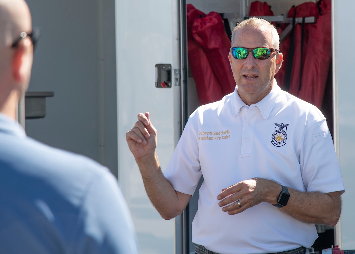 A fire chief stands out side in front of a trailer.