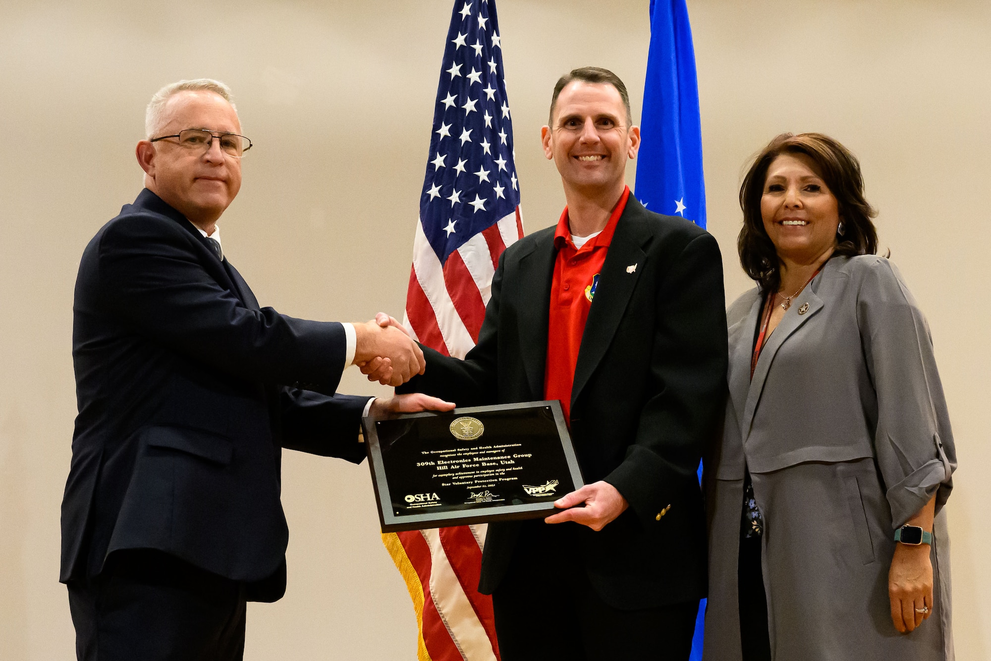 Left to right, Phillip Smith, OSHA Salt Lake Technical Center director, presents Daniel Posch, 309th Electronics Maintenance Group director, and Michelle Hathaway, Ogden Air Logistics Complex deputy director, with a plaque.