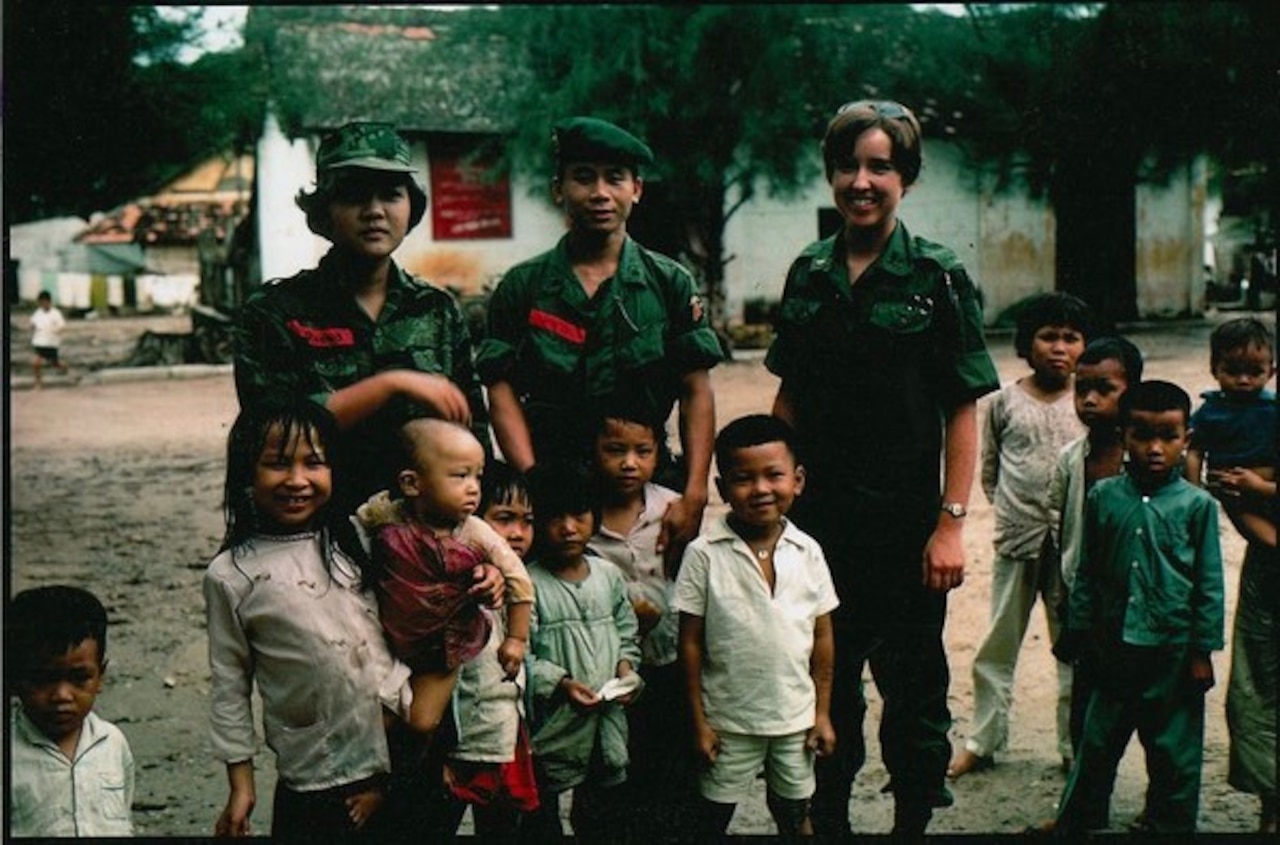 Three adults stand with several children to pose for a photo.