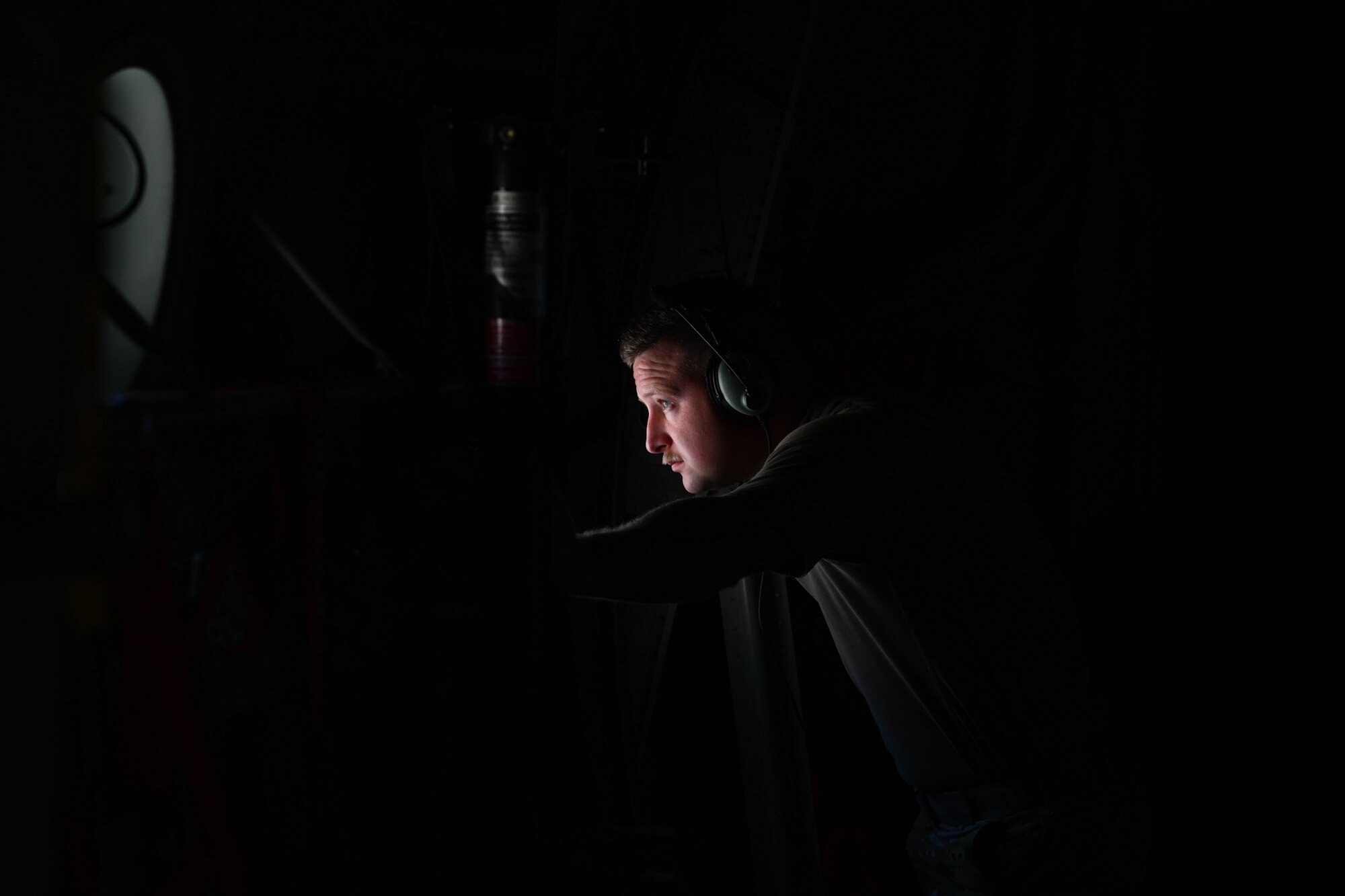 A U.S. Airman looks out the window of a C-130J aircraft.