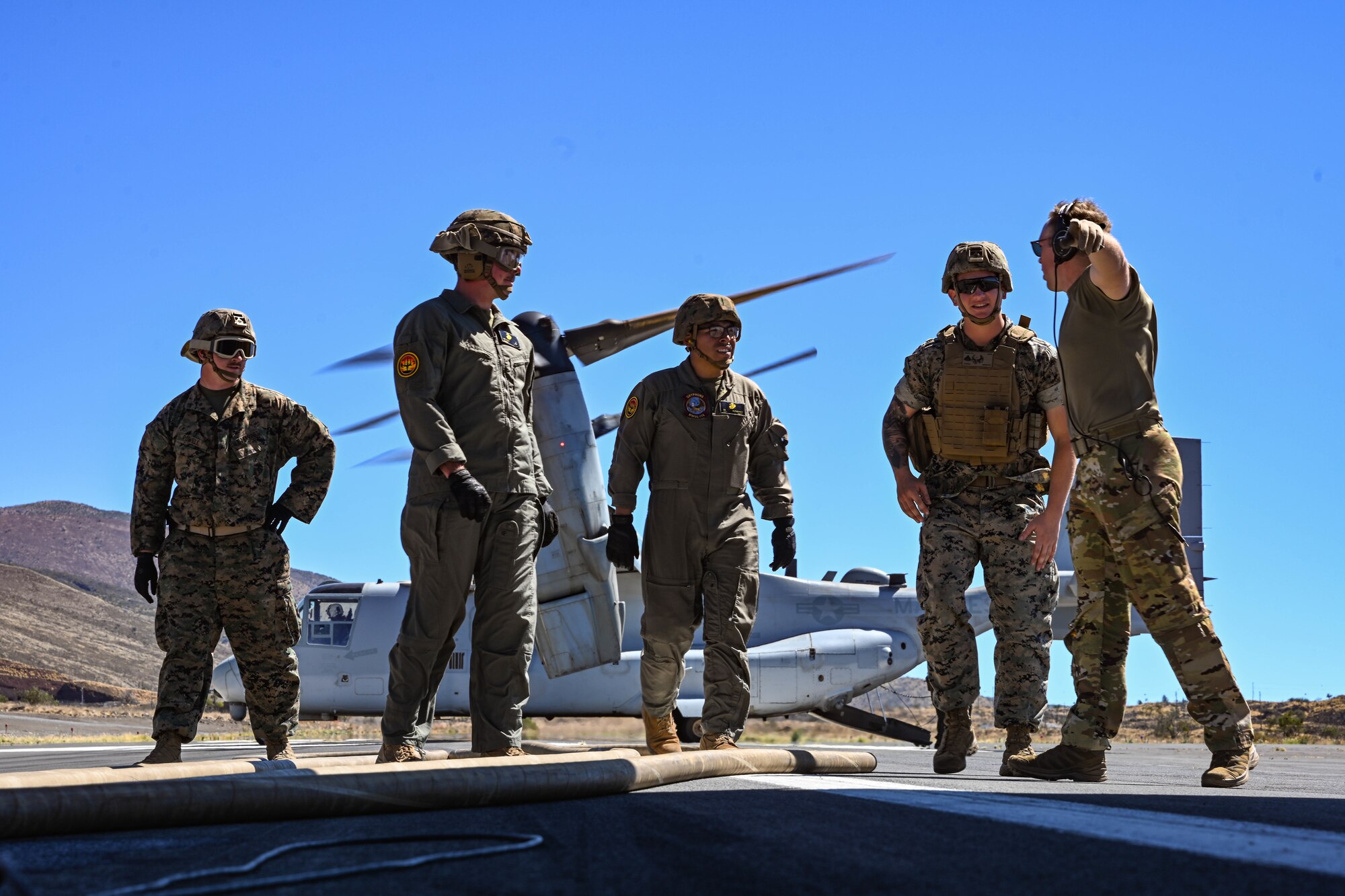 U.S. Marines and U.S. Airmen stand in front of MV-22B Osprey while conducting Forward Area Refueling Point operations.
