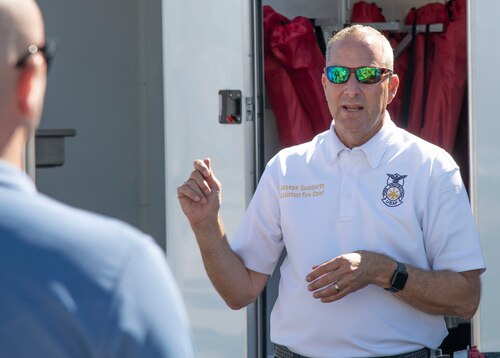 A fire chief stands out side in front of a trailer.
