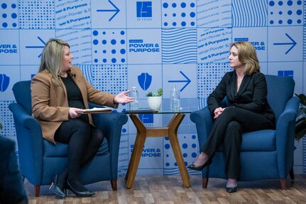 Two women face each other in conversation while seated.