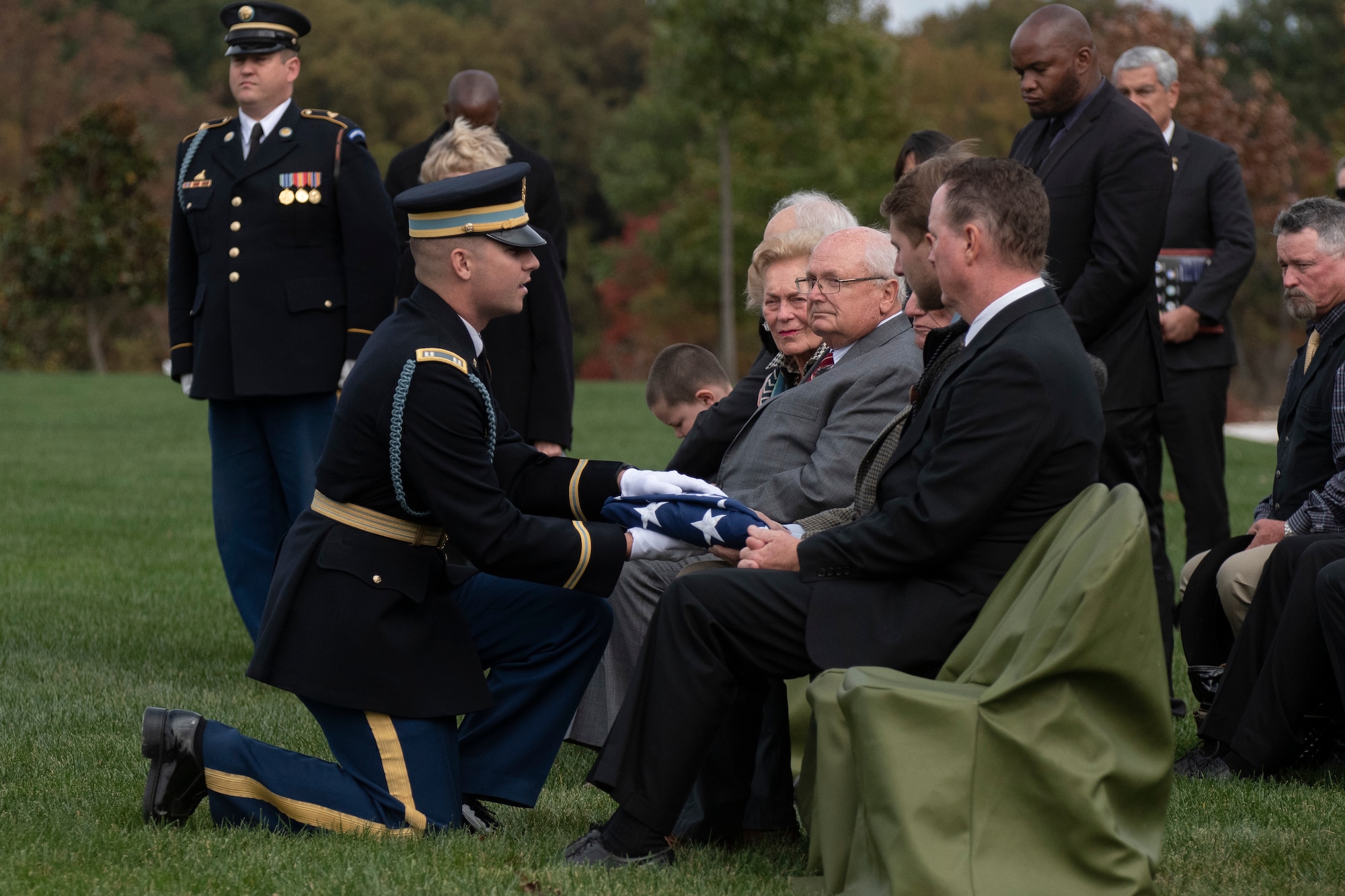 A man hands off a folded flag to a family member.