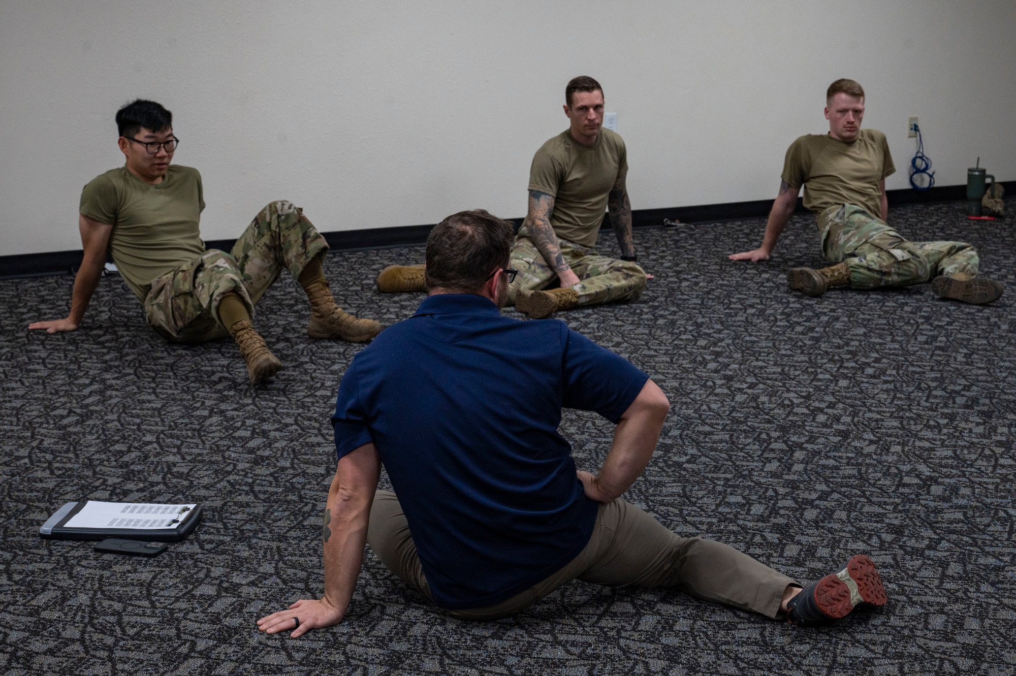 A man instructs Airmen about how to perform a stretch.