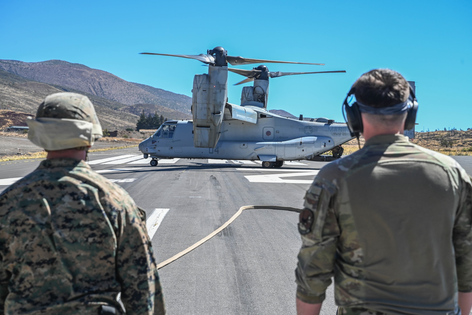A U.S. Marine and a U.S. Airman look at a MV-22B Osprey while conducting Forward Area Refueling Point operations.