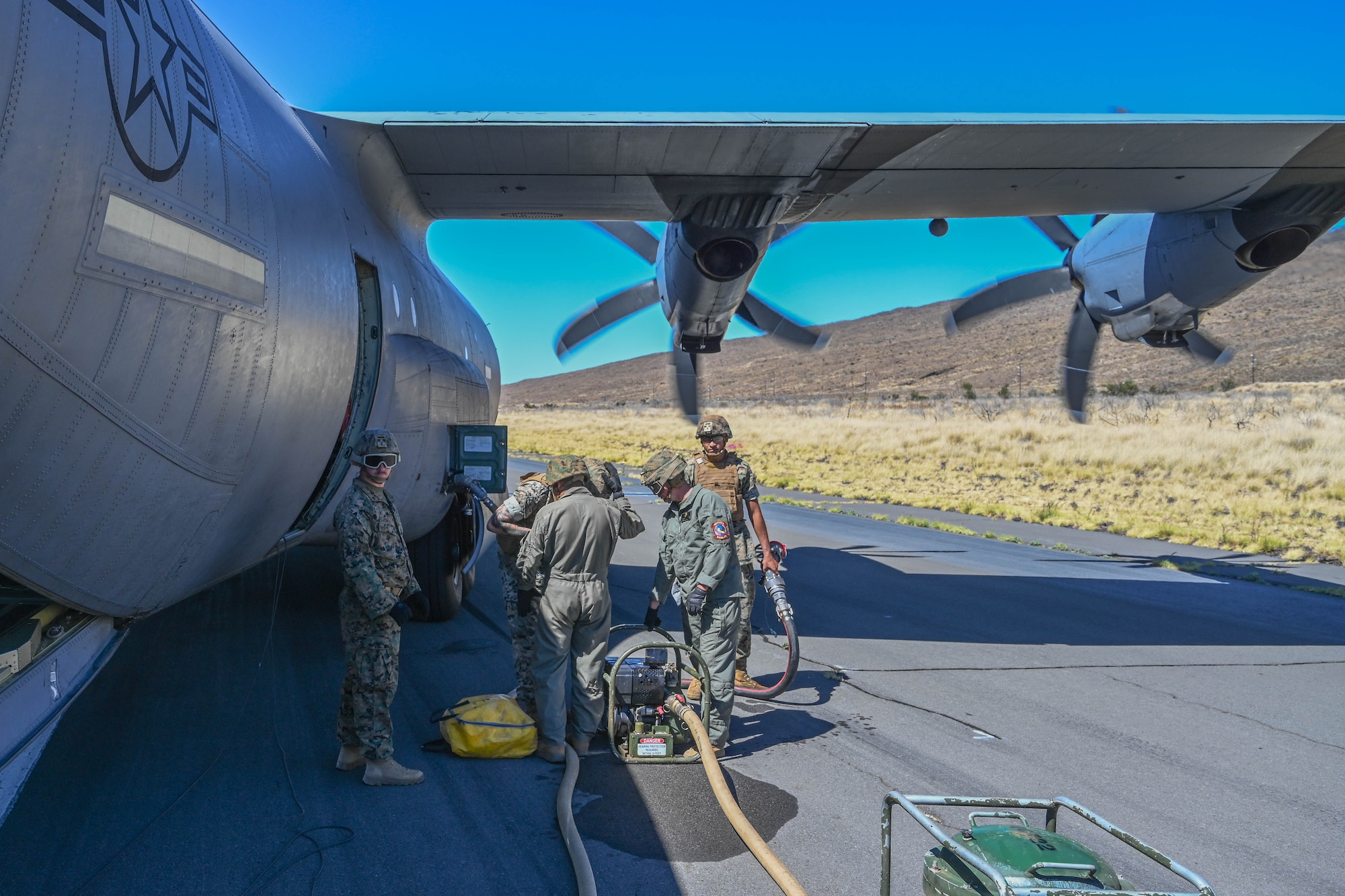 U.S. Marines stand by the wing of a C-130J aircraft while conducting Forward Area Refueling Point operations.