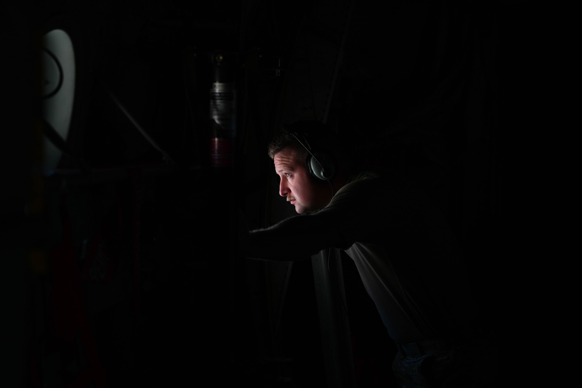 A U.S. Airman looks out the window of a C-130J aircraft.