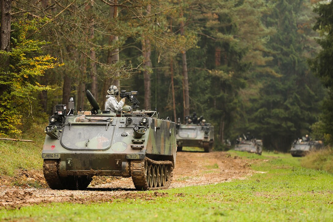 Soldiers ride in tanks down a road during a training mission.