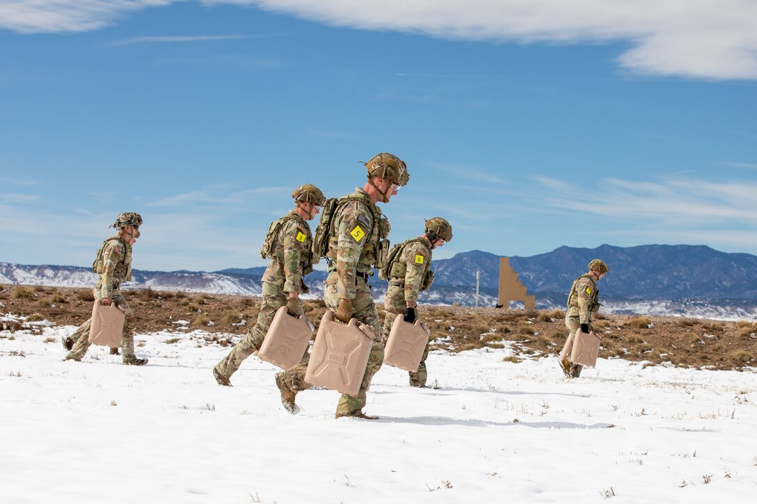 Soldiers carry large containers of water across a snowy landscape.