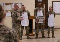 Command Sgt. Maj. Nicholaus Fordham, the command sergeant major of the 198th Combat Sustainment Support Battalion and the full-time Illinois Army National Guard logistics sergeant major, presented the coin of Chief Warrant Officer 4 Tollie Yoder, the U.S. Army National Guard food advisor, to Staff Sgt. Justin Hill of Robinson, Illinois; Spc. Jordan Robinson of Danville, Illinois; and Spc. Samantha Vazquez of Norwood, Illinois.