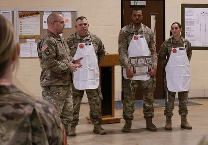 Command Sgt. Maj. Nicholaus Fordham, the command sergeant major of the 198th Combat Sustainment Support Battalion and the full-time Illinois Army National Guard logistics sergeant major, presented the coin of Chief Warrant Officer 4 Tollie Yoder, the U.S. Army National Guard food advisor, to Staff Sgt. Justin Hill of Robinson, Illinois; Spc. Jordan Robinson of Danville, Illinois; and Spc. Samantha Vazquez of Norwood, Illinois.