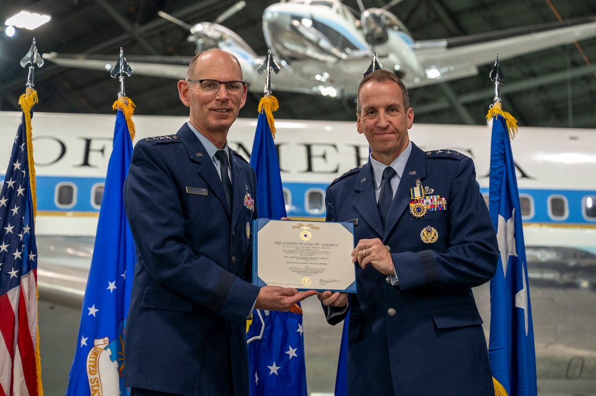 Two men stand on stage with certificate in Air Force uniforms.