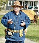 Illinois State Military Museum volunteer John Werner of Chatham, Illinois, explains how the World War I uniform he is wearing found a new use in World War II when the U.S. used it as the uniform for enemy prisoners of war.