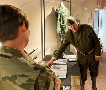 J. Perkins, a volunteer with the First Infantry Division Museum at Cantigny Park in Wheaton, Illinois, explains to Illinois Army National Guard Chief Warrant Officer 3 Kelly Malcom how U.S. Soldiers also served in places such as Siberia and Italy during World War I in addition to France.