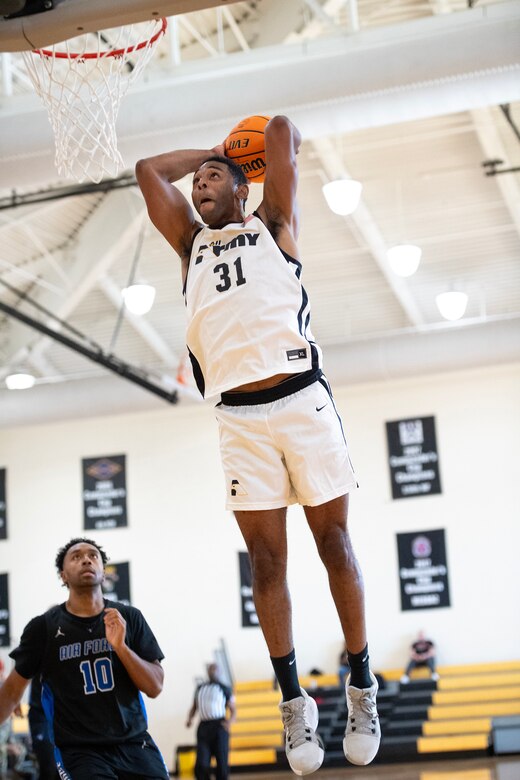 A soldier slam dunks a basketball.