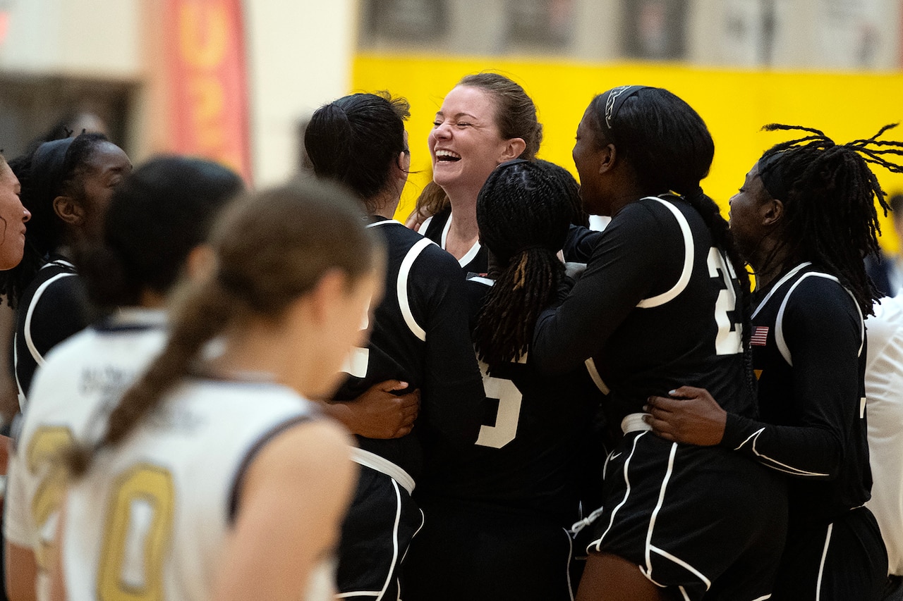 Service members celebrate on a basketball court.