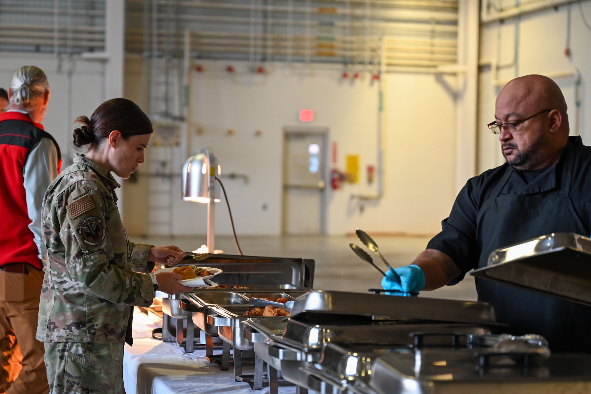A U.S. Airman fills her plat with food in a buffet line.
