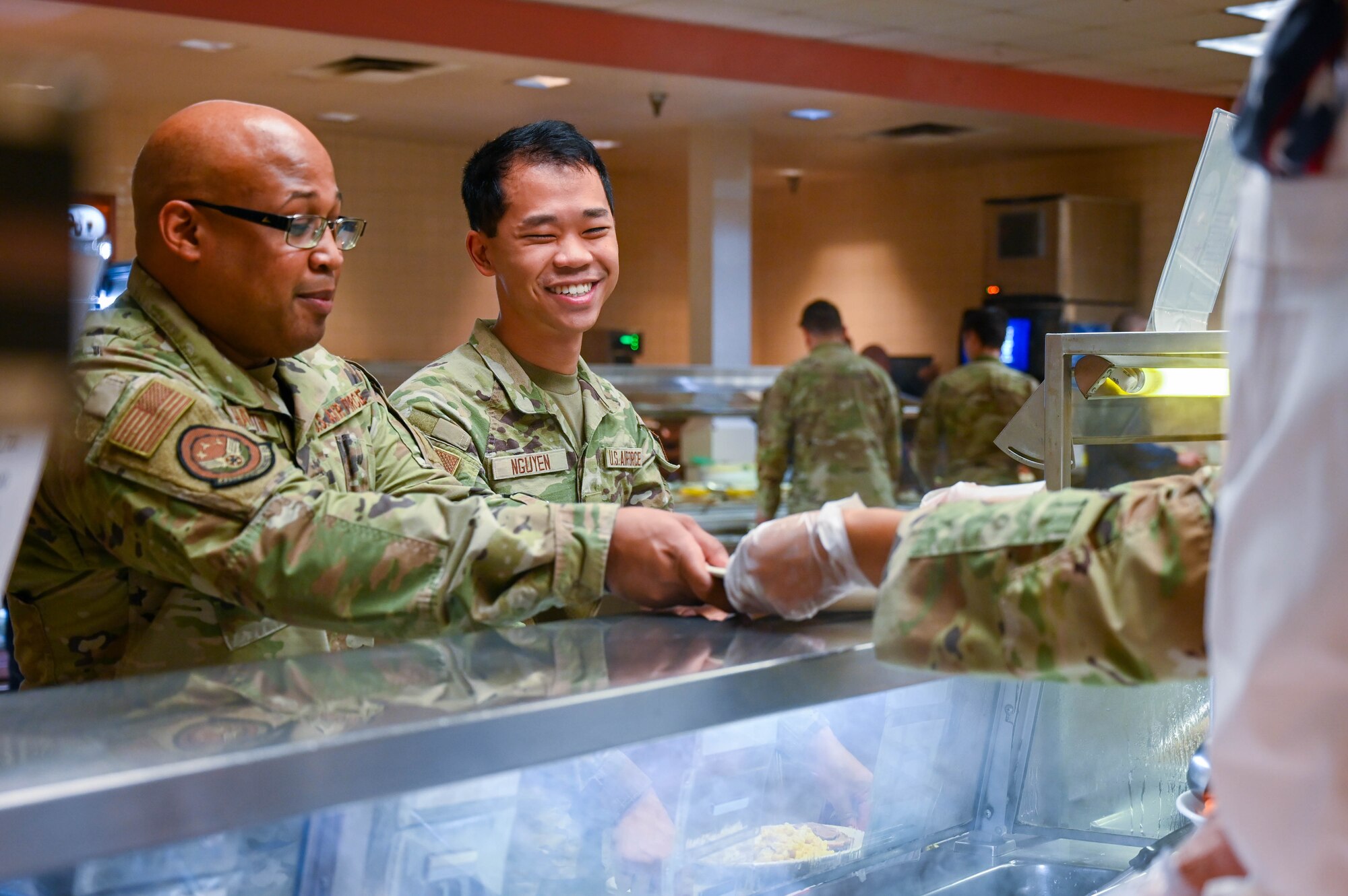 Tech Sgt. Mycha Hamilton and Senior Airman Tim Nguyen, 433rd Airlift Wing Maintenance Squadron, receive meals from a senior leader during the “Feed the Airmen” Luncheon event at Joint Base San Antonio-Lackland, Texas, Nov. 4, 2023.
