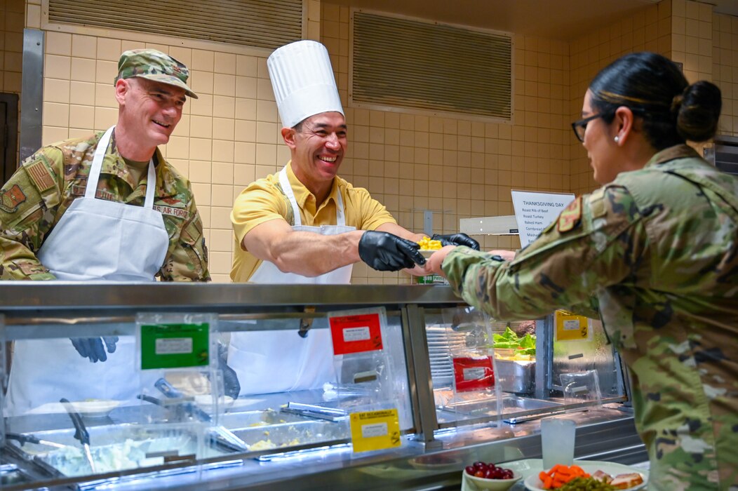 Col. William Gutermuth, 433rd Airlift Wing commander, alongside San Antonio Mayor Ron Nirenberg, 433rd AW Honorary Commander, hands a dish to Staff Sgt. Adriana Barrientos, 433rd AW public affairs specialist, during the “Feed the Airmen” Luncheon event at Joint Base San Antonio-Lackland, Texas, Nov. 4, 2023.