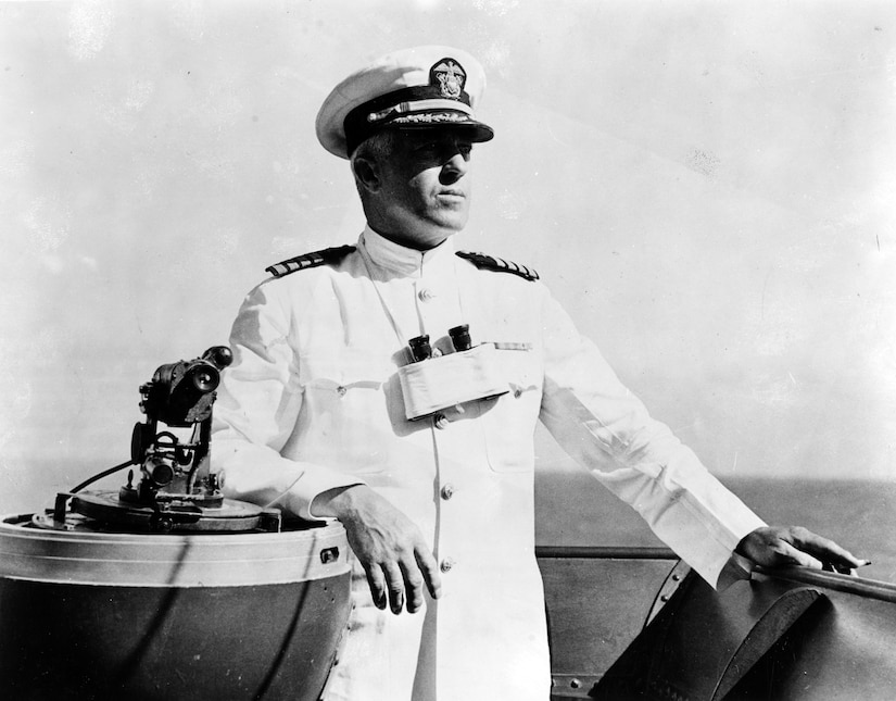 A man in uniform stands on the bridge of a ship.