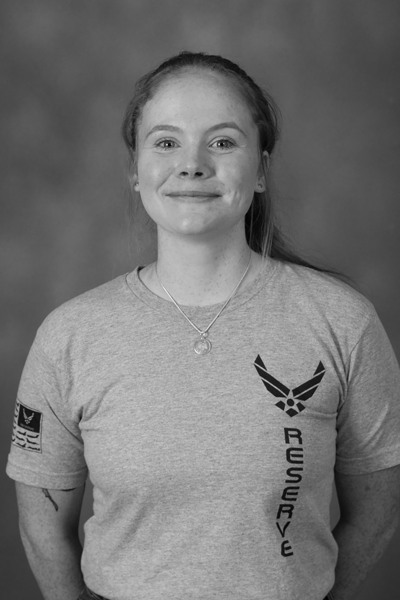 Black and white photo of an Airman smiling in front of a background