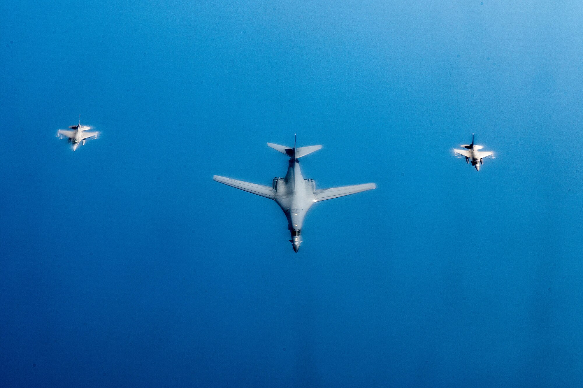 A B-1 Lancer flies in formation with an F-16C Fighting Falcon escort over the Red Sea.