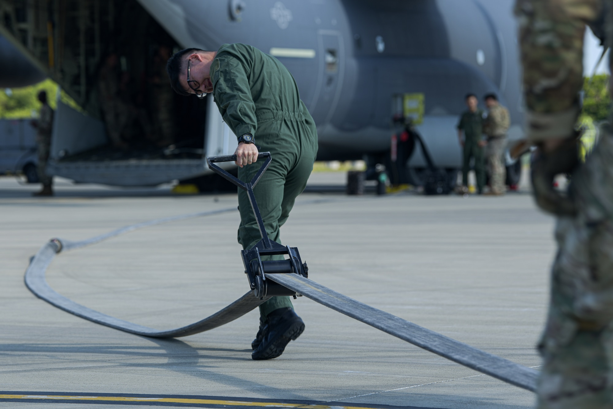 A Japan Air Self-Defense Force service member squeegees a fuel hose during Rescue Flag Okinawa 2023 at Kadena Air Base, Japan, Oct. 27, 2023.