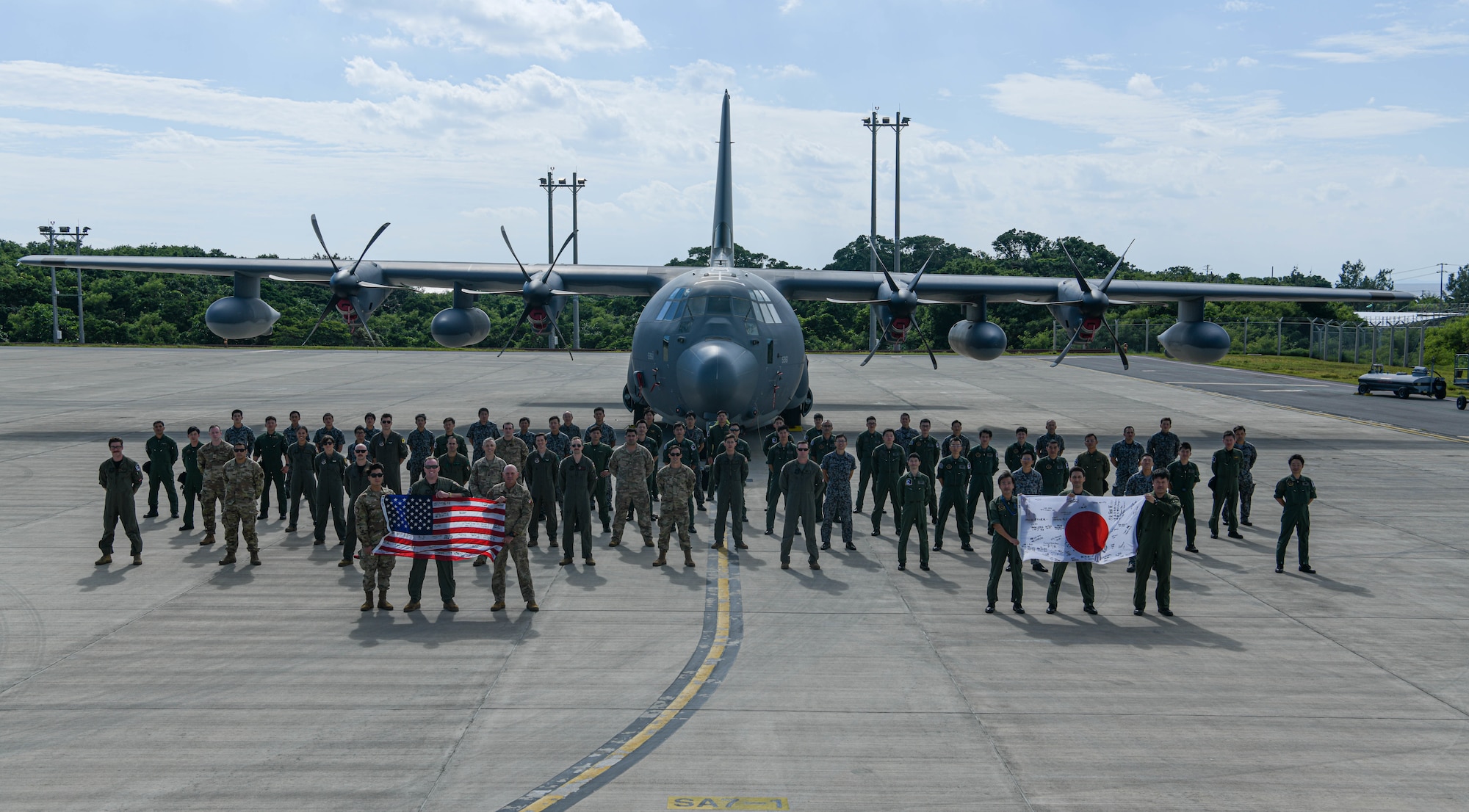 A Japan Air Self-Defense Force service member passes a fuel hose to a U.S. Air Force service member.