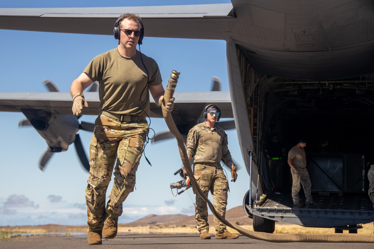 An Airman carries a fuel hose.