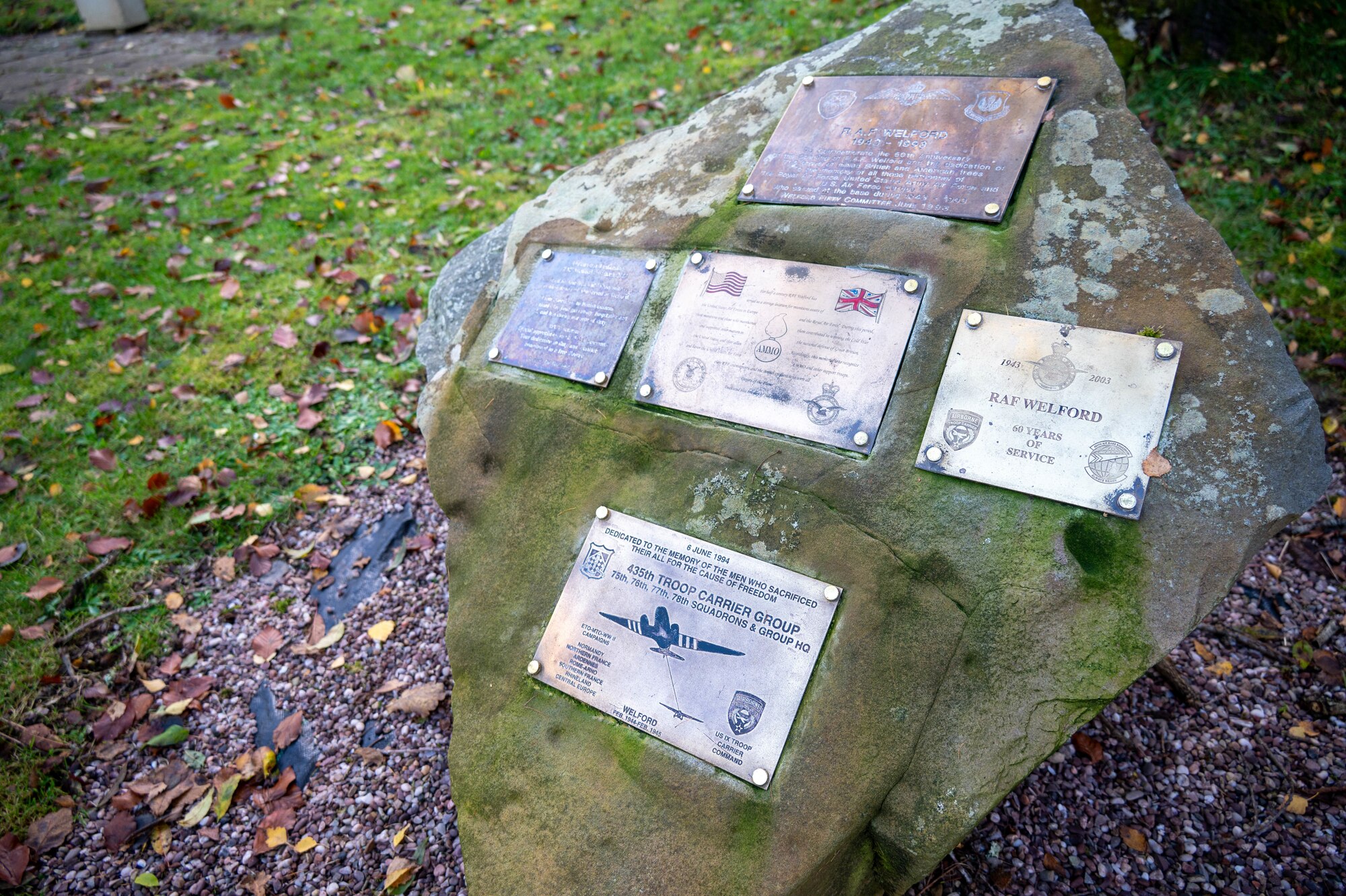 A large rock with five memorial plaques.