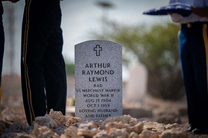 Several uniformed service members stand around a gravesite.