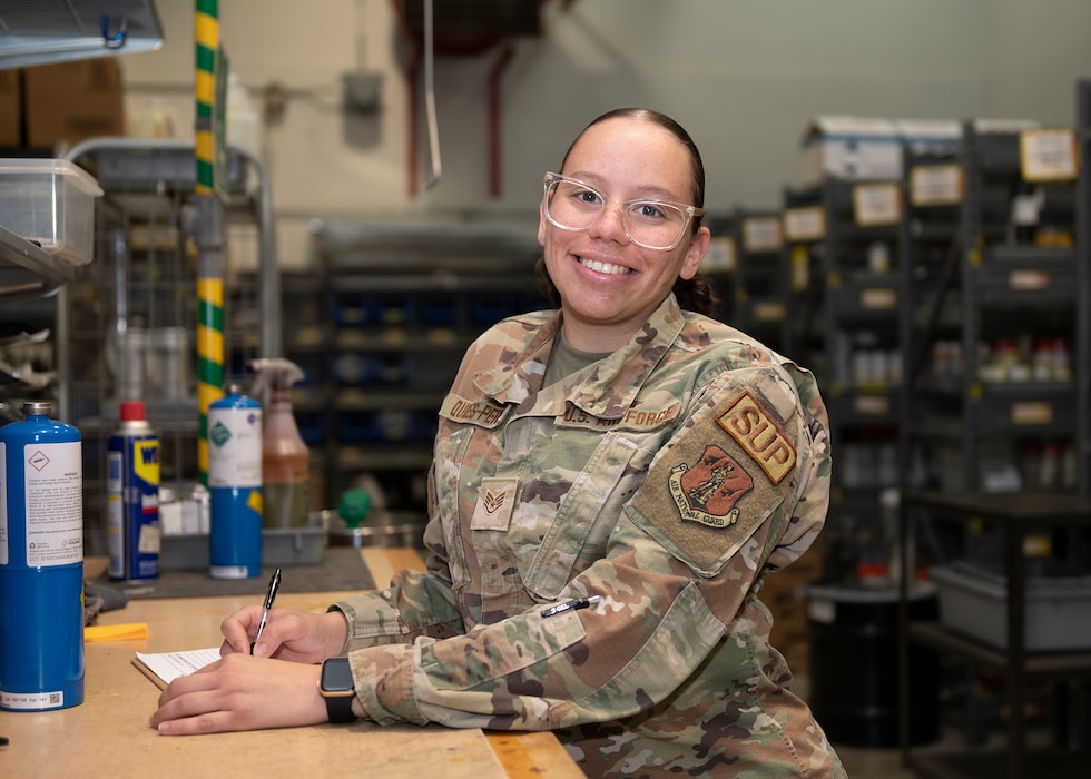 A female Airman stands at a desk in a hazardous materials warehouse