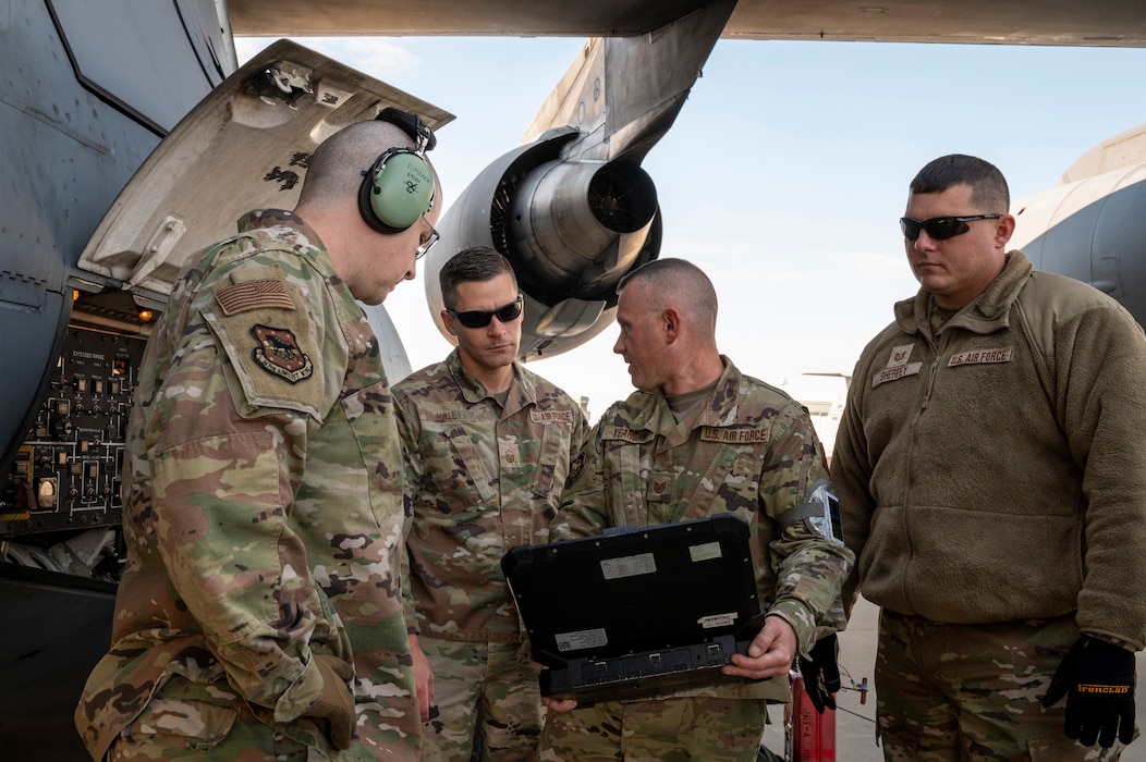 Four Airmen stand beside a cargo aircraft