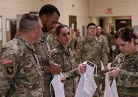 Chief Warrant Officer 3 Melissa Downey, the Illinois Army National Guard's food service officer, presents aprons to three Soldiers for their culinary achievements.